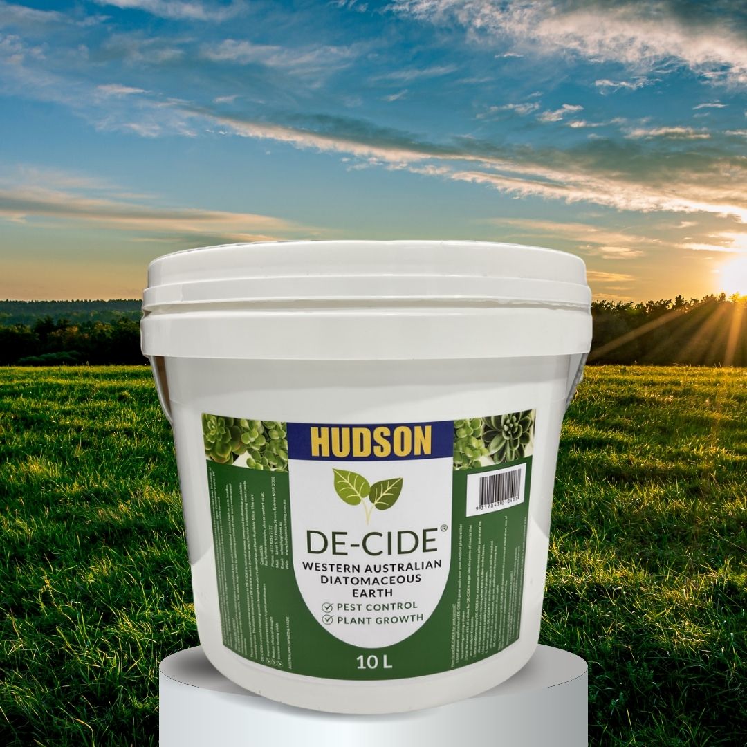 A white tub with the DE-CIDE Diatomaceous Earth label. Background of a grassy farmland with a sunset hidden by trees in the distance.